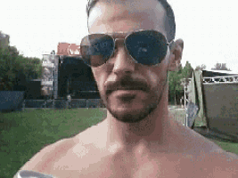 a shirtless man with a beard wearing sunglasses