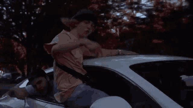 a man in a pink shirt is sitting in a car