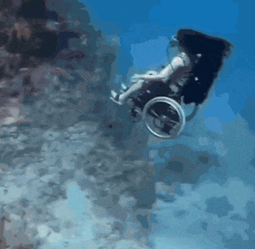 a man in a wheelchair is swimming underwater