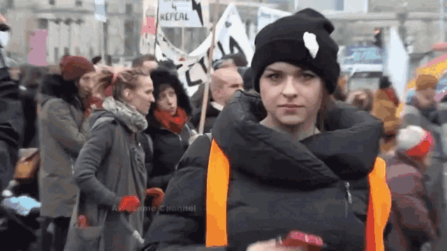 a woman stands in front of a crowd holding a sign that says " repeal "