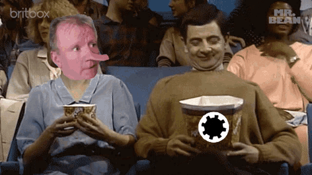 a man with a long nose is sitting next to a man holding a bucket of popcorn