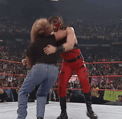 two men are wrestling in a wrestling ring in front of a crowd of people .