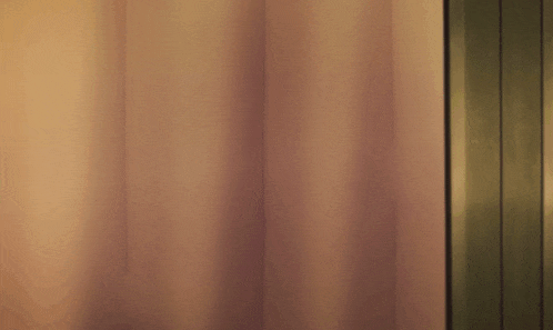 a girl with purple eyes is peeking out behind a curtain