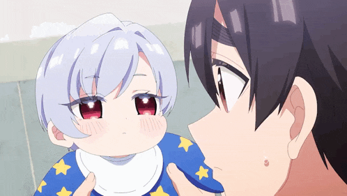 a man is feeding a baby with a blue bib with stars on it