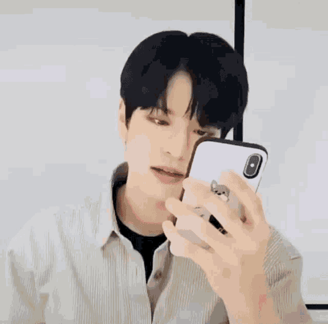 a young man is holding a cell phone in his right hand .