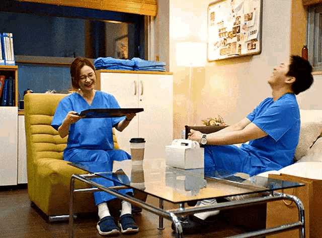 a man and a woman in scrubs are sitting on a couch and laughing