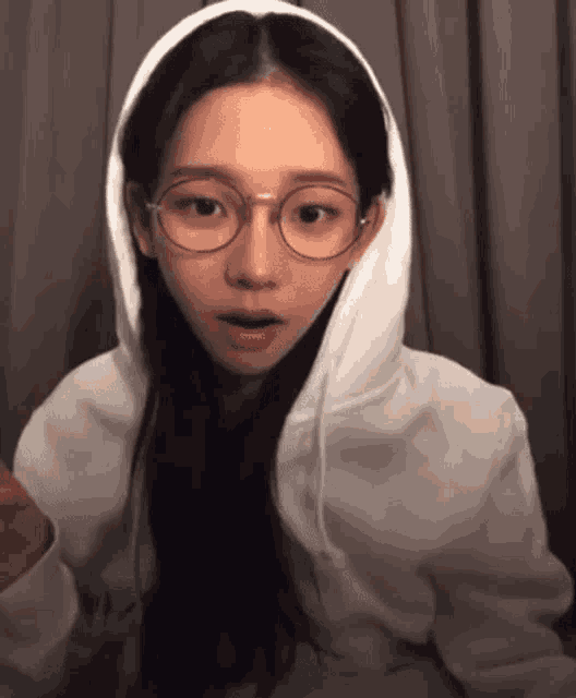 a woman wearing glasses and a white hoodie with a hood .