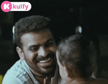 a man with a beard is smiling and looking at another man with a kolfy logo in the corner