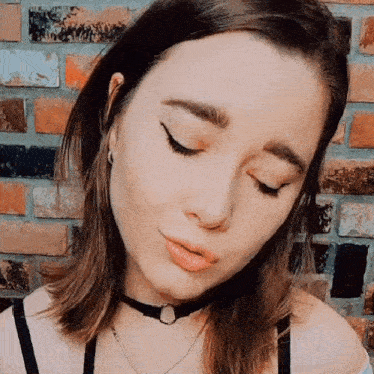 a close up of a woman 's face with her eyes closed and a choker necklace .