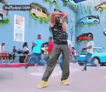 a man is dancing in front of a crowd of people in a parking lot .
