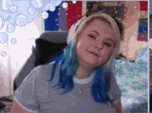a woman with blue hair is wearing headphones and a grey shirt