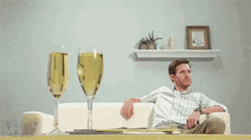 a man is sitting on a couch while a woman pours a glass of wine