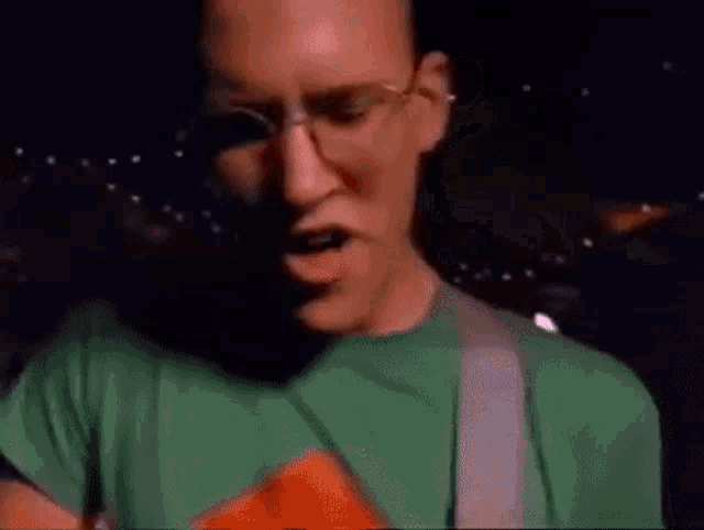 a man with glasses and a green shirt is making a funny face .