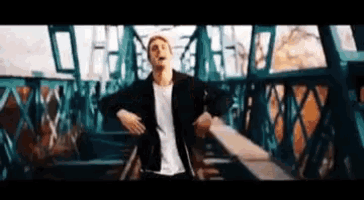 a man is dancing on a bridge with his arms outstretched .