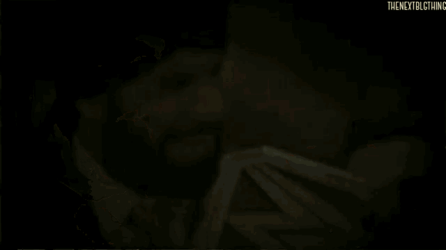 a man with a beard is holding a wrestling championship belt and smiling .