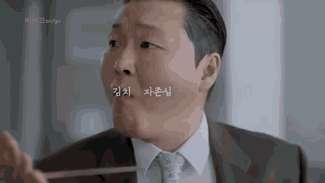 a man in a suit and tie is holding chopsticks in his mouth .