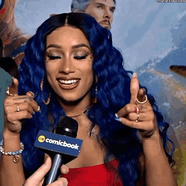 a woman with blue hair is talking into a microphone that says comicbook
