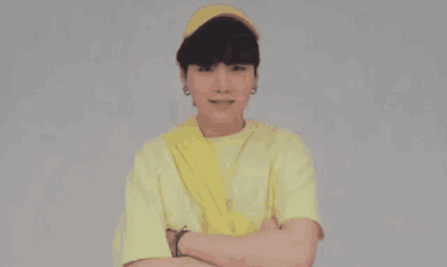 a young man wearing a yellow hat and a yellow t-shirt is holding his hand to his chin .