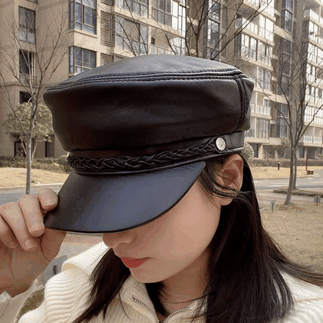 a woman wearing a black leather hat with braided trim