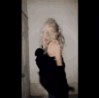 a woman with blonde hair is standing in front of a door