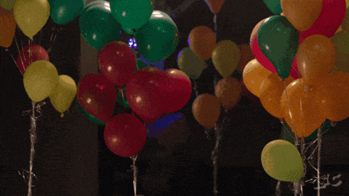 a bunch of balloons are floating around a person holding a box