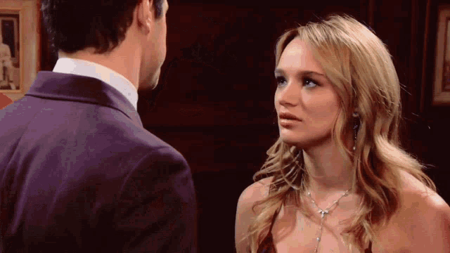 a man in a suit and a woman in a dress are looking at each other