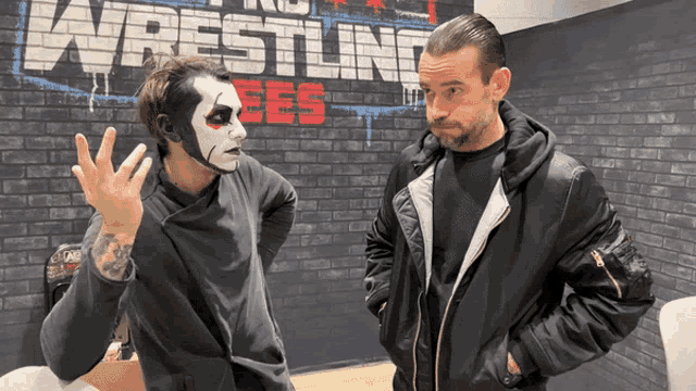 two men standing in front of a sign that says wrestling on it