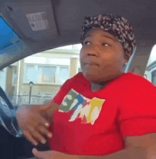 a woman in a red shirt and head scarf is sitting in a car .