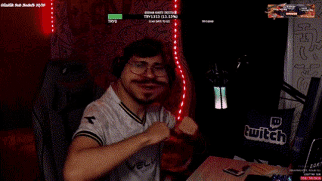 a man is sitting in front of a computer with a twitch logo in the background