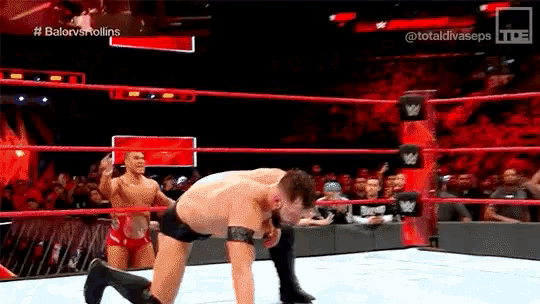 two men are wrestling in a wrestling ring with a crowd in the stands watching .