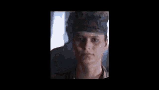 a woman in a military uniform is looking at the camera with a shadow on her face .