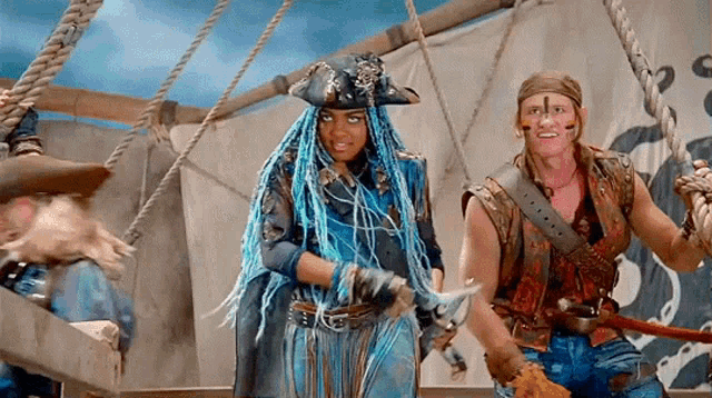 a woman with blue hair and a pirate hat is standing next to a man holding a sword .