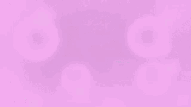 a man wearing headphones is sitting in front of a computer screen with pink bubbles coming out of it .