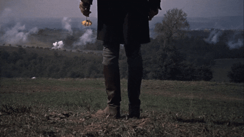 a man is standing in a field with smoke coming out of the ground