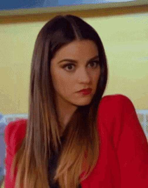 a woman wearing a red jacket is making a funny face
