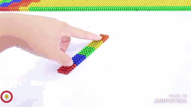 a person is holding a piece of colorful magnetic beads