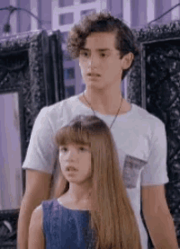 a boy and a girl are standing next to each other and looking at something .