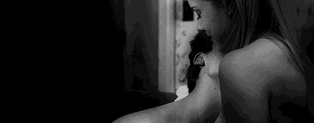 a man and a woman are kissing in a black and white photo .