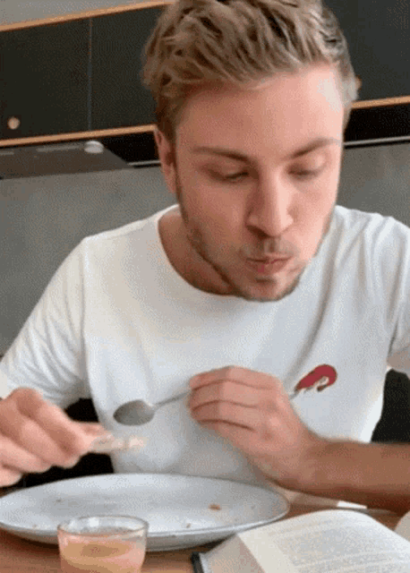 a man wearing a white shirt with a lobster on it is eating food