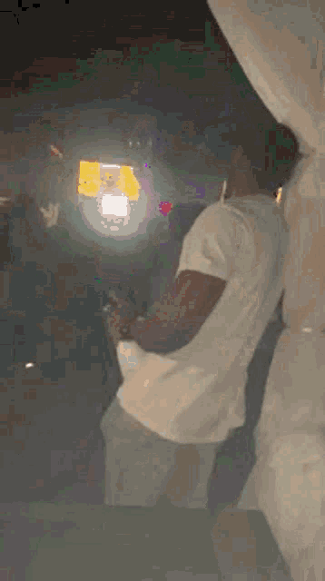 a man in a white t-shirt is dancing in a dark room .