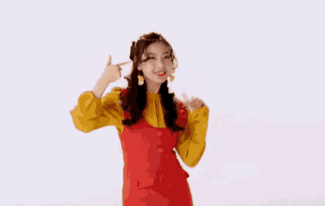 a woman in a red dress and yellow shirt is dancing and pointing at herself .