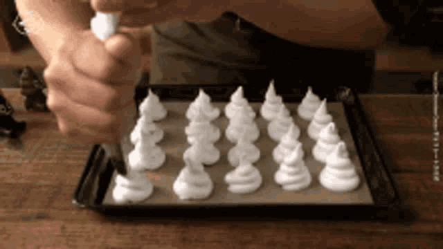 a person is piping white frosting onto a tray