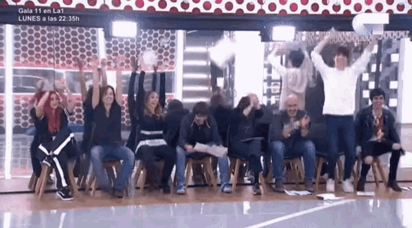 a group of people sitting in chairs with their arms in the air