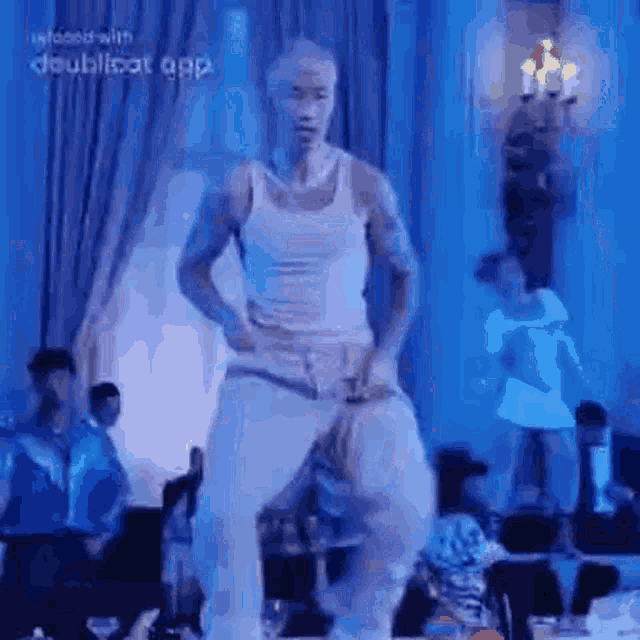 a man is dancing on a stage in front of a crowd in a room .