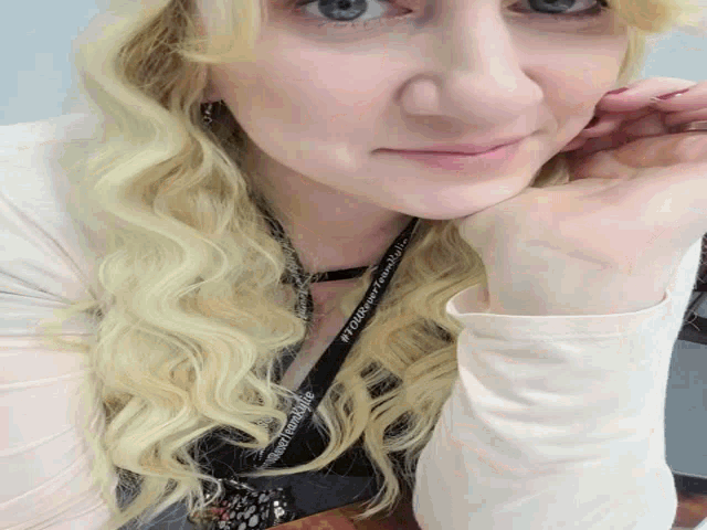 a woman with blonde hair wearing a lanyard that says # 1 on it