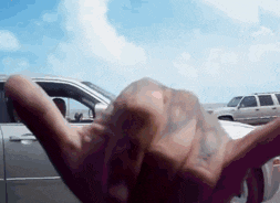 a person 's hand is reaching out towards a car