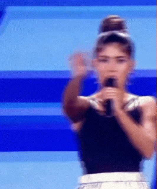 a woman is singing into a microphone on a stage