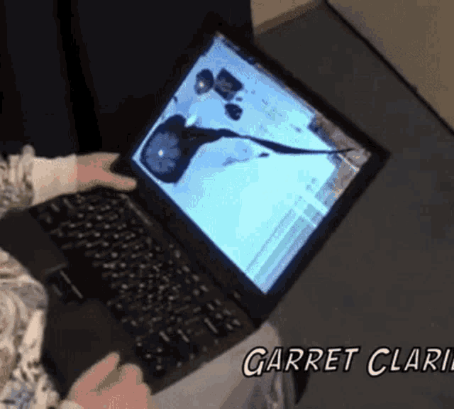 a person is using a laptop that has a broken screen and the name garret clark written on the bottom