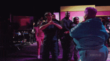 a group of people are standing around a person wearing a blue hoodie that says just