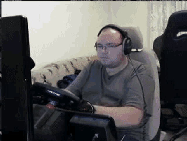 a man wearing headphones sits in front of a computer monitor